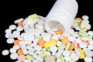medical drugs and pills are scattered on a black table