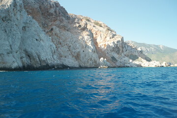 Turquoise water in the Mediterranean sea. Rocky cliff in the clear sea water. Calm waves wash huge rocks.