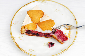 Closeup piece of homemade berry pie with meringue and cookies on white wooden table. Shallow focus.