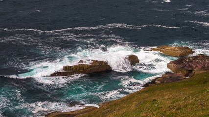 Stoer lighthouse view on wild ocean waves rocks