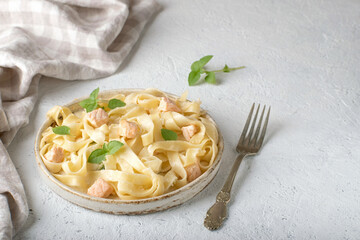 Salmon pasta in a ceramic plate on a light background