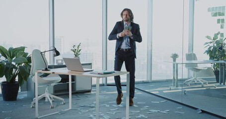 Emotional young happy positive businessman celebrating rich day salary receiving huge earnings making money rain dancing in corporate office.