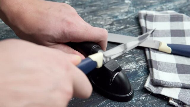 sharpen a kitchen metal knife with a grindstone. Home household knife sharpening.