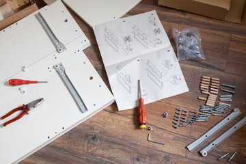 Furniture assembly parts and tools for self assembly furniture, on the floor.