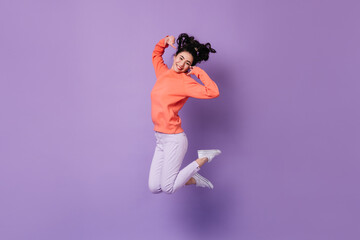 Pleased japanese girl jumping on purple background. Studio shot of blissful asian young woman.