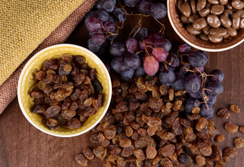 Dried raisins with a bunch of grapes on the table top view stock images. Raisins sultanas still life photo images. Drying grapes and raisins in chocolate images