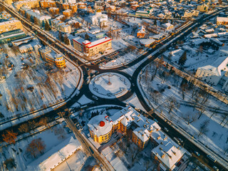Fototapeta premium Aerial view of roundabout road with circular cars in small european city at winter sunset