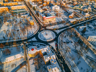 Fototapeta premium Aerial view of roundabout road with circular cars in small european city at winter sunset