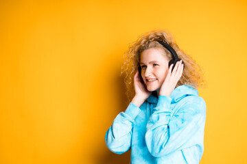 Naklejka premium Happy girl listening to music with headphones pressing them to ears looking to the side