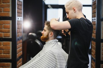 Close-up, master hairdresser does hairstyle and style with scissors and comb. Concept Barbershop.