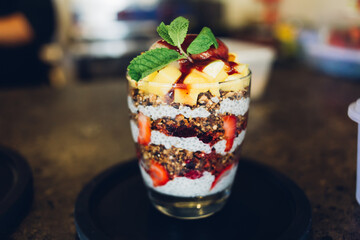 Greek yogurt with homemade granola, fresh berries and fruits on wooden background in a glass on a wooden table.Yogurt and chia parfaits. Healthy foods providing probiotics. Selective focus.