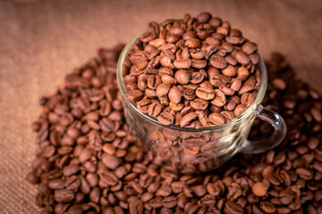 Roasted coffee beans with a glass coffee cup on a dark background