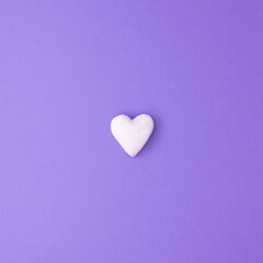 Fototapeta premium Square love concept idea with small white heart on purple background. Minimal flat lay.