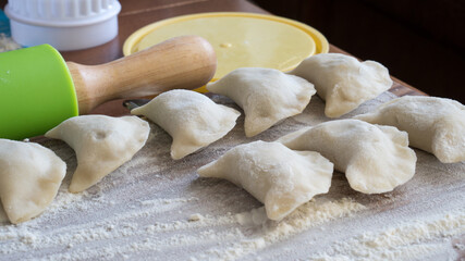 Raw dumplings on a wooden board on grey table 