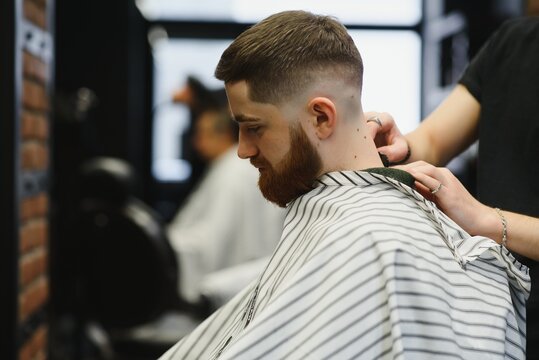 Close up image of barber shaving a man with a sharp steel razor.