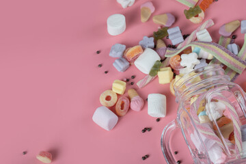 Colorful marshmallows and jellybeans on a pink background