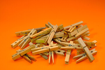 Set of wooden clothespins that appear one by one on an orange background.
