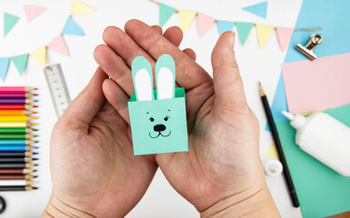 Step-by-step instructions for making a bunny box from colored paper. Step 7 - glue the ears to the...