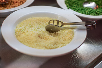 White plate with grated cheese at buffet restaurant, closeup detail