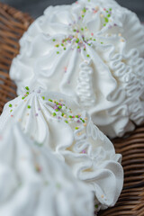 White floral meringue cookies with coconut powder in a wooden basket