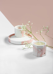Creative composition with scented candles of soy wax in a concrete candlestick on a pink and white paper background. Eco-friendly. Minimalism. Natural. Dried flowers. Cozy shadow.