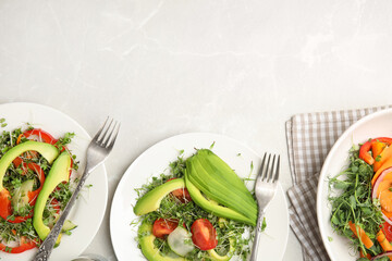 Delicious vegetable salads with avocado and microgreen served on light table, flat lay. Space for text