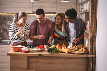 Fiends preparing vegetarian meal.They preparing food and making fun in the kitchen.Home party.
