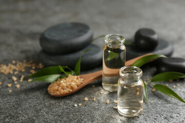 Beautiful composition with essential oil and spa stones on grey table, closeup