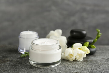 Beautiful spa composition with cosmetic products, stones and flowers on grey table