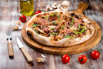 Pizza Carbonara with bacon, arugula and chanterelles. On a wooden background.