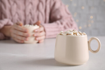 Cup of delicious hot cocoa with marshmallows on white table, space for text