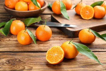 Fresh ripe tangerines with green leaves on wooden table