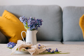White retro jug with hyacinths on a white table.