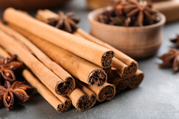 Aromatic cinnamon sticks and anise on grey table, closeup