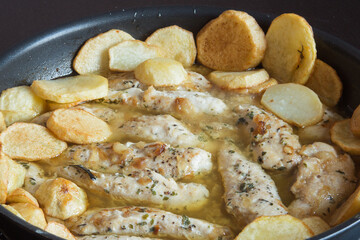 Frying pan with beef tenderloins, potatoes, and spices in green sauce. Food and meat.