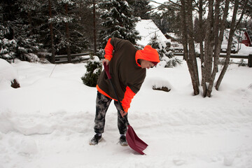 Young man cleans the yard after a snowfall. guy shoveling snow. 