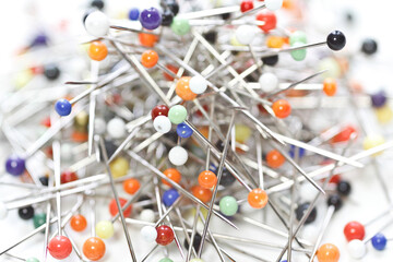 Multicolored sewing pins laid loose on white background