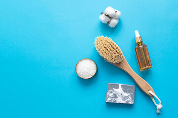 Wooden brush with natural cactus bristles for dry body massage, salt for scrubbing, soap and a pedicure file on a blue background close-up. Eco-friendly lifestyle and zero waste concept.