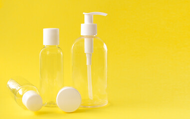 Plastic transparent cosmetic bottles with a white lid on a yellow background.