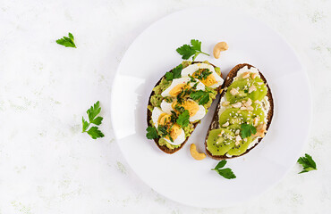 Vegetarian breakfast. Sandwich with avocado puree, boiled eggs and sandwich cream cheese, kiwi, nuts.  Healthy breakfast or lunch. Top view, overhead