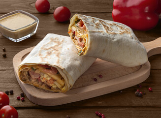 Shawarma with meat on a wooden board. Chicken meat in pita bread. Pita bread with meat and vegetables.