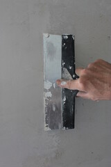 Hand using a spatula, level the putty on the wall.