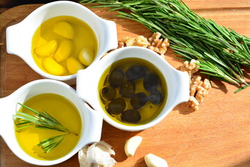 garlic in olive oil. black olive in oil. with herb rosemary walnuts on a wooden board