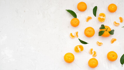 Tangerines: whole and lobules with green leaves on white table. Good harvest of ripe and large tangerines has been harvested. Mandarins are delicious fruits that are healthy and rich in vitamins. 