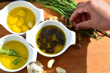 herbs and spices olive oil with garlic olive oil with black olive and walnuts on a wooden board with hand on a walnuts