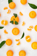 Obraz premium Tangerines: whole, cut and lobules with leaves on white table. Fruit contains many vitamins that are beneficial for healthy lifestyle. Close-up