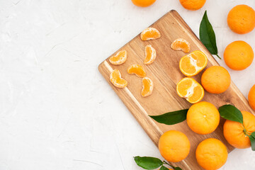 Tangerines: whole, cut and lobules on chopping board with leaves on white table. Prepare wonderful, fresh juice every day to promote health and replenish body with vitamins. Close-up
