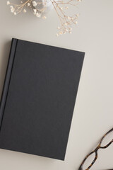 Black book mockup with a dried gypsophila decoration on the beige table.