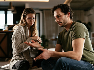 Young man checking empty wallet, no money. Unemployed sad man sitting at home with wife showing empty wallet.