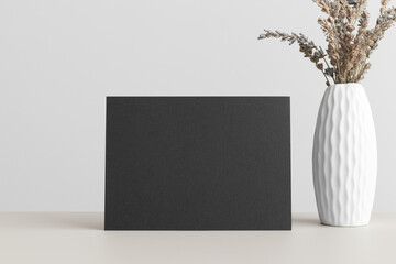 Black invitation card mockup with a dried lavender on the beige table. 5x7 ratio, similar to A6, A5.